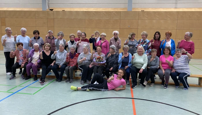 Gruppenfoto der Gymnastik-Frauen, die mit einem Gläschen Sekt auf ihr 60-jähriges Jubiläum anstoßen